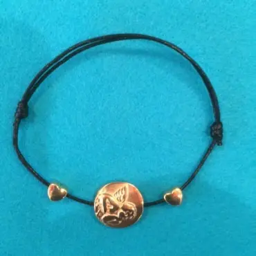Bracelet médaille ange doré posé à plat sur feutrine turquoise, la médaille à l'angelot entre deux cœurs
