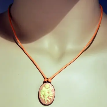 Collier camée rose porté par un buste couleur chair, cordon orange noué au-dessus du camée