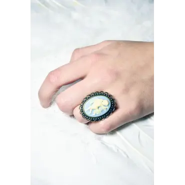 Bague au camée bleu clair portée sur une main posée dans des plumes blanches
