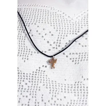 Le collier Cupidon en entier, pendentif tourné sur son dos plat, cordon en V sur dentelle blanche