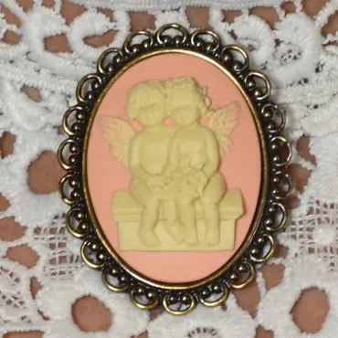 Broche camée style victorien : deux anges sur un banc, fond rose, cadre vieux bronze