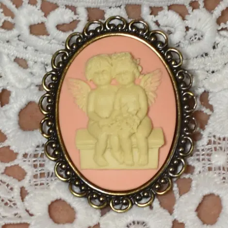 Broche camée style victorien : deux anges sur un banc, fond rose, cadre vieux bronze
