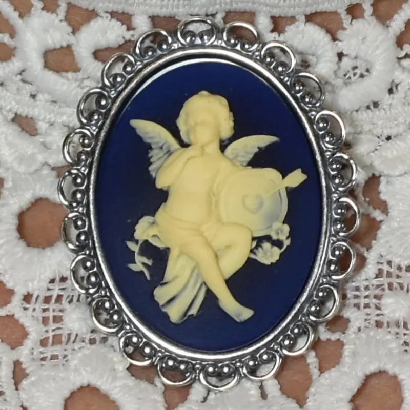 Fond bleu nuit et relief ivoire : l'ange, un doigt au menton, et sa cible percée d'une flèche