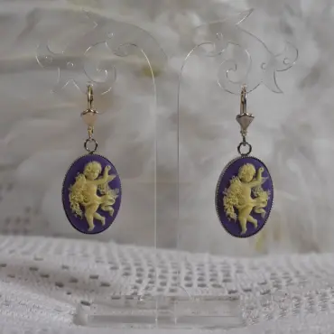 Pendants camée violet sur leur présentoir, fond de plumes blanches