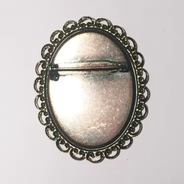 Dos de la broche sertie vieux bronze, avec son épingle sur un fond plein