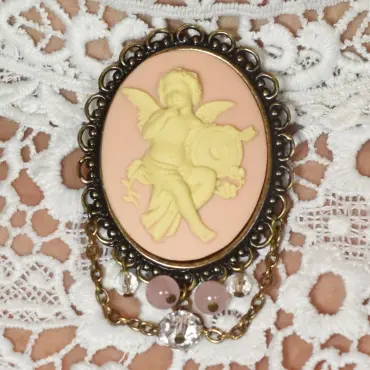 Broche châtelaine « L'Amour » vieux bronze, coloris rose, sur une dentelle blanche