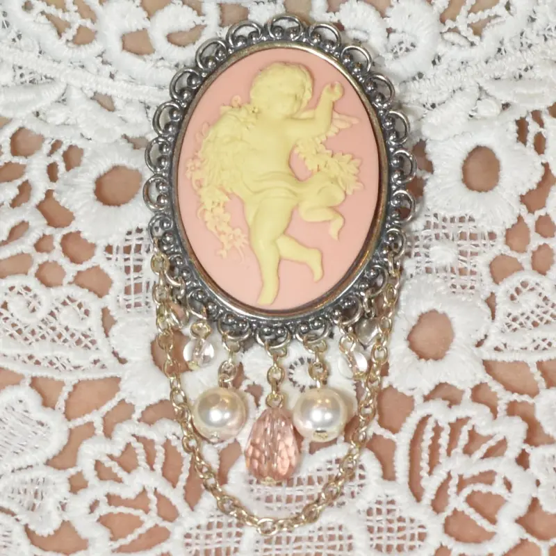 Broche châtelaine vieil argent « La Danse » rose, posée sur une dentelle blanche