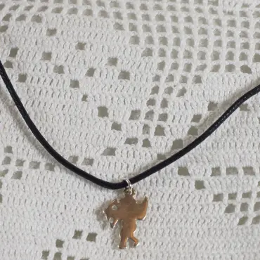 Dos plat et uni du pendentif Cupidon, au bout de son cordon noir, sur dentelle au crochet