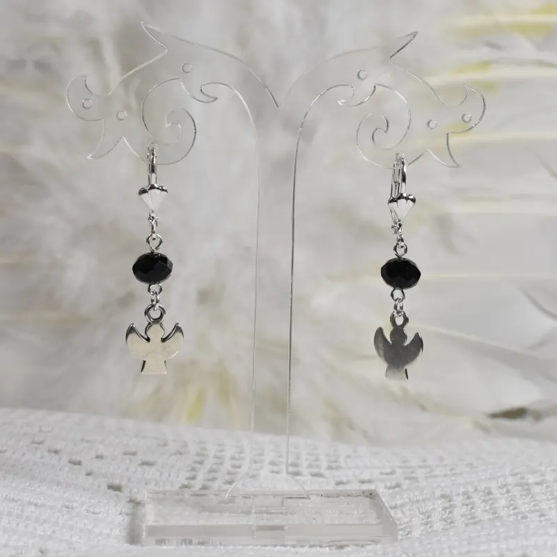 Boucles d'oreilles ange Silhouette, perle noire à facettes, sur un présentoir transparent