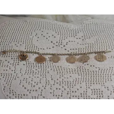 Gourmette ange tendue à l'horizontale sur dentelle : la médaille ajourée, puis cinq médailles dessinées