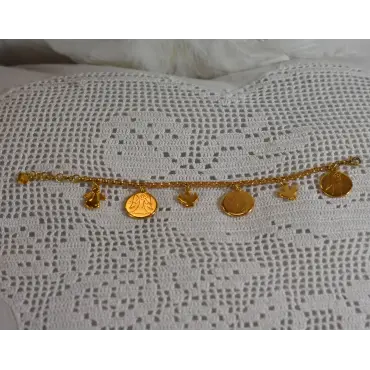 Bracelet 6 médailles doré tendu de face sur dentelle, breloques alignées, rallonge au cœur à gauche