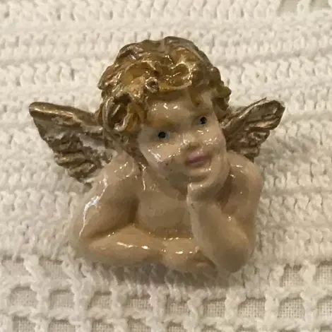 Broche angelot Raffaello de face : buste peint, cheveux et ailes dorés, menton dans la main