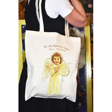 Tote bag citation « Le Sourire » porté à l'épaule, sur une robe noire et un tee-shirt blanc