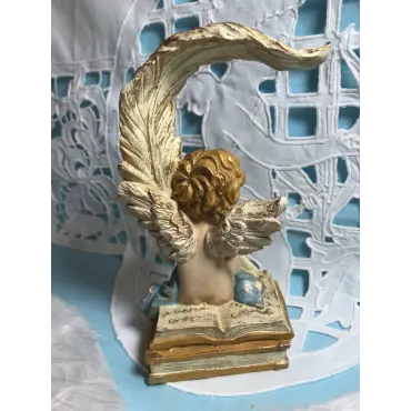 L'Ange écrivain droite de dos, assis sur un livre ouvert aux lignes d'écriture