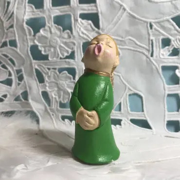 Figurine ange choriste vert printemps de face, mains jointes, devant une broderie ajourée